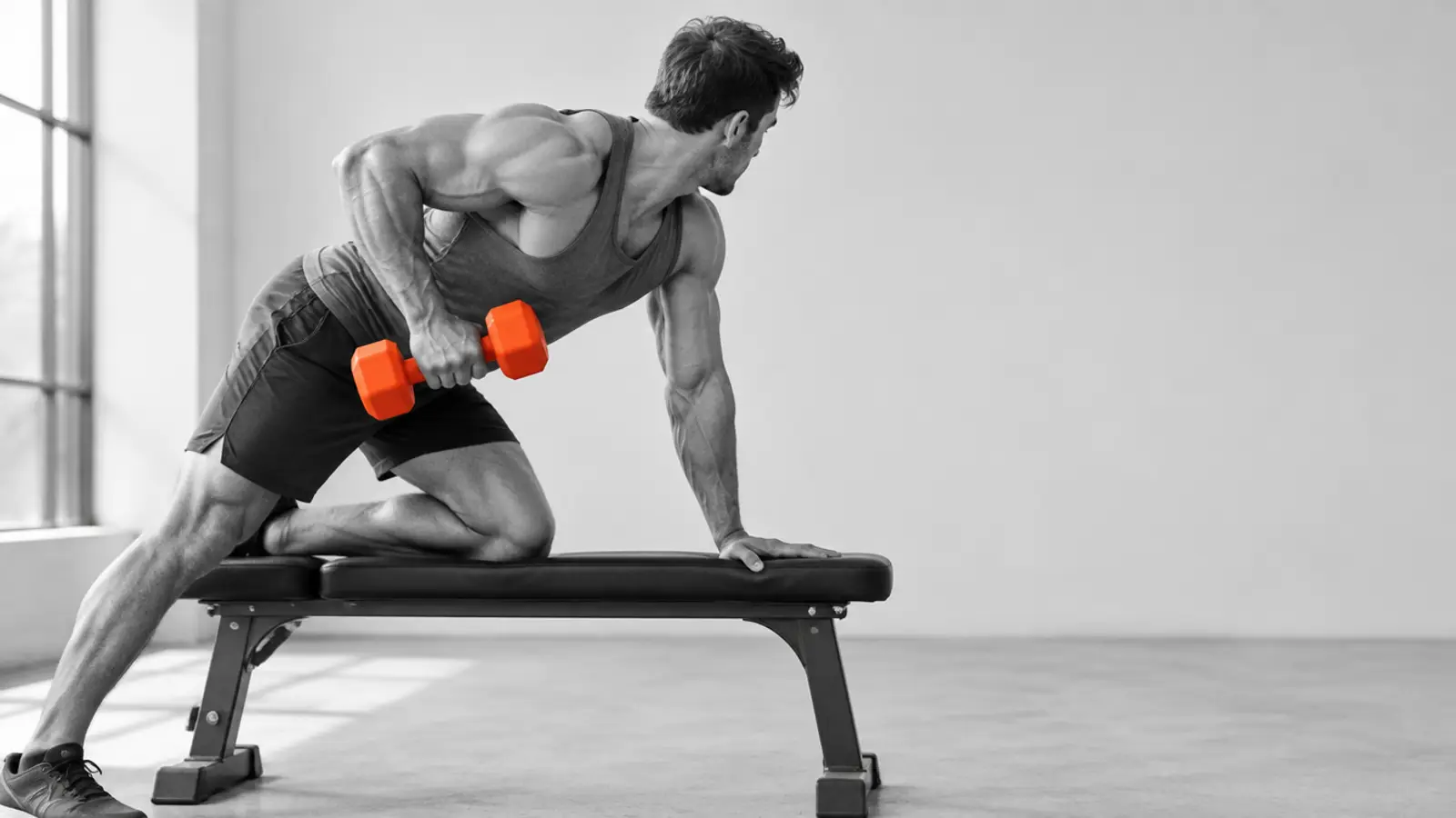 Muscular athlete training with dumbbells in a gym