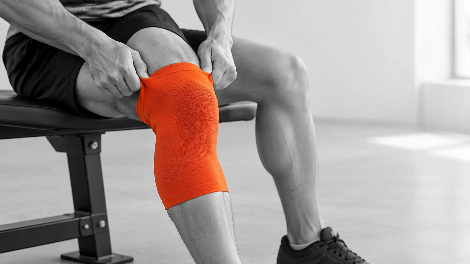 Athlete pulling on a knee sleeve before a training session