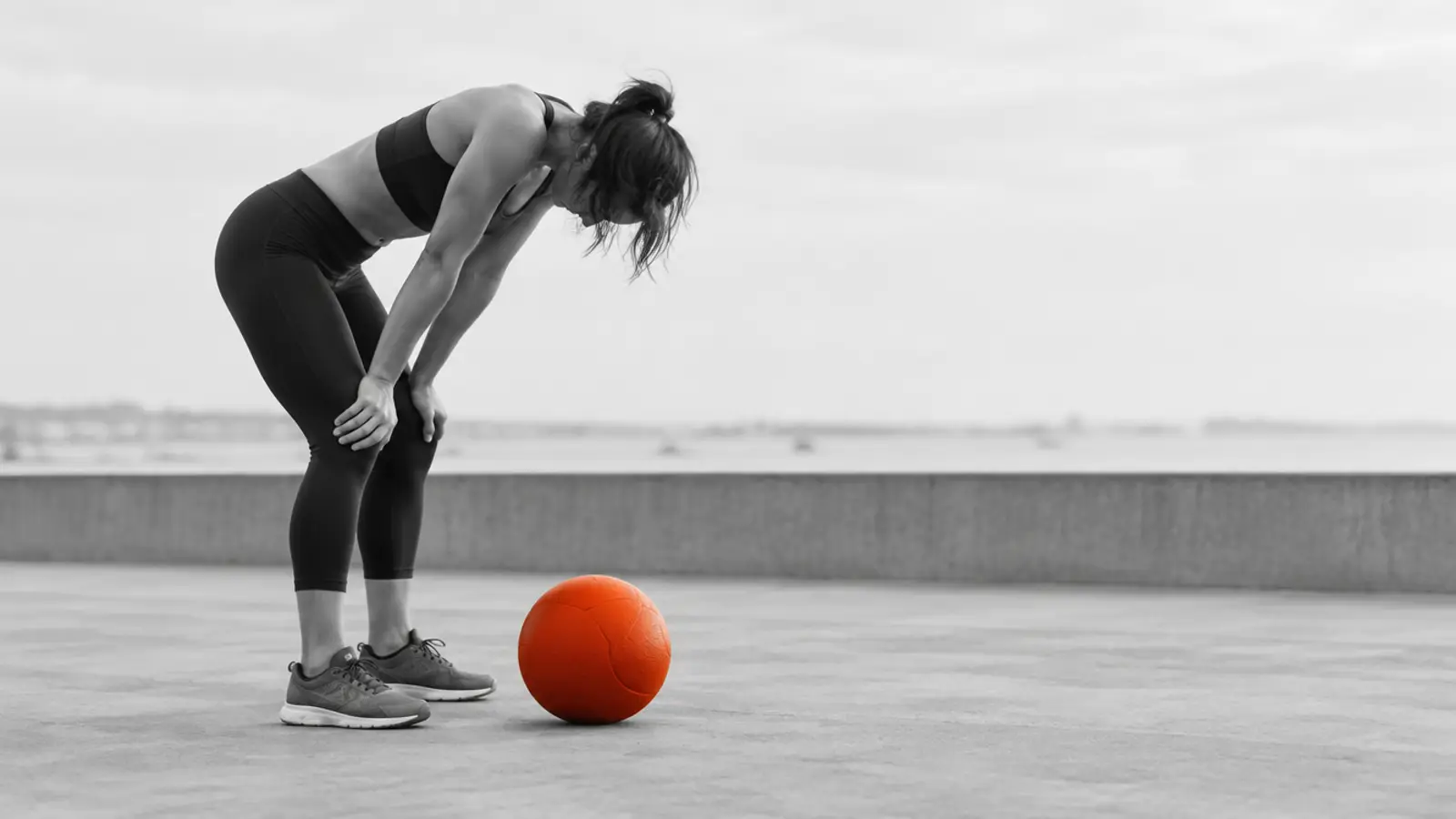 Exhausted athlete with hands on knees beside a dropped wall ball